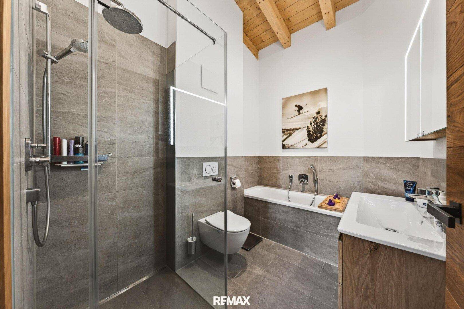 Modernes Badezimmer mit begehbarer Dusche, Badewanne und eleganten Fliesen.