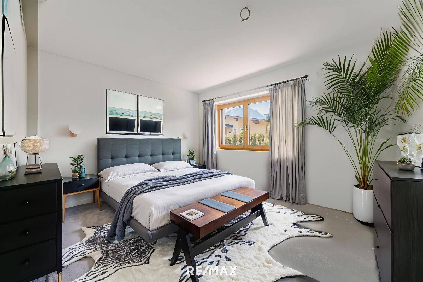 Helles Schlafzimmer mit großem Bett, moderner Einrichtung und Blick ins Grüne.