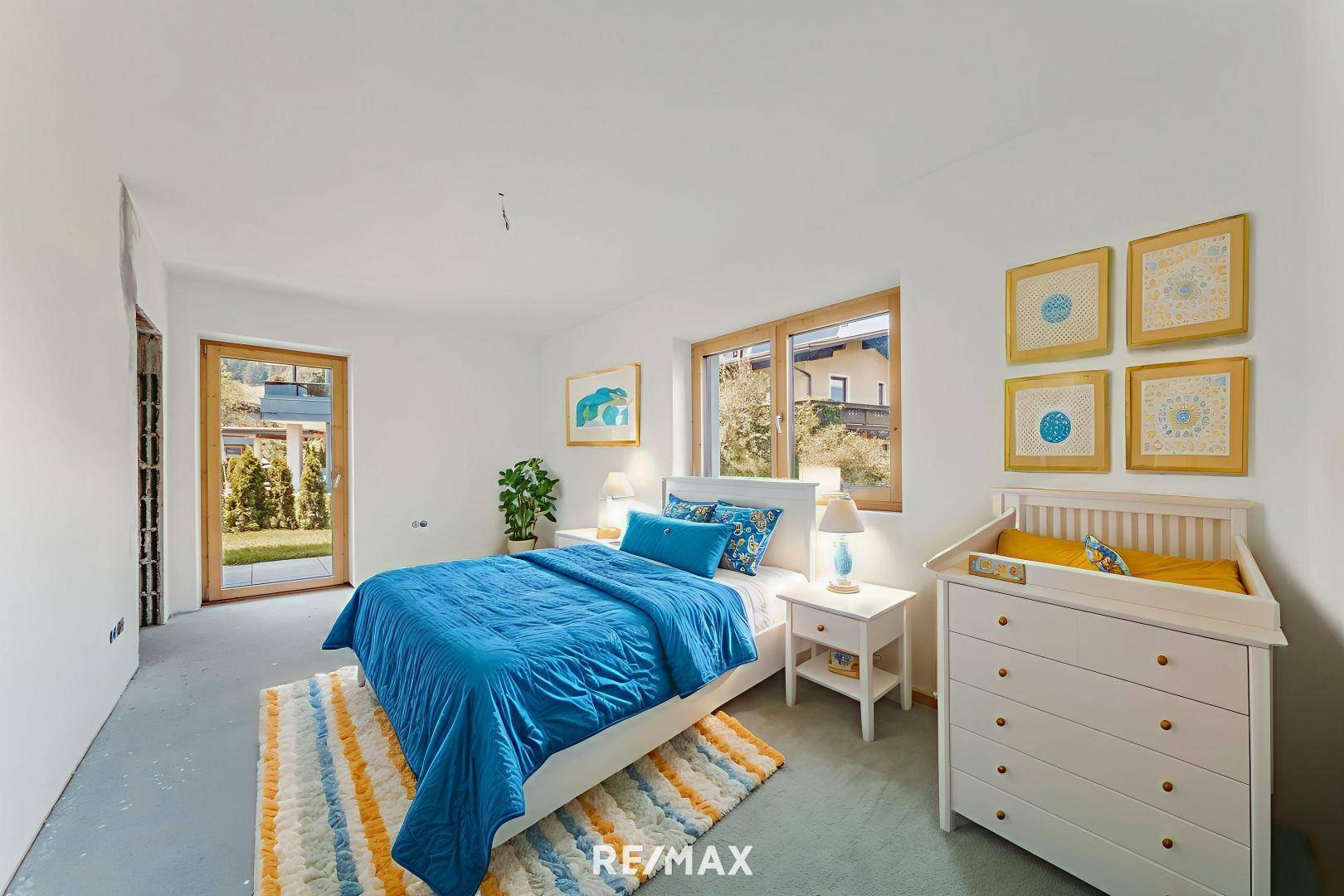 Freundliches Schlafzimmer mit blauem Bett, Wickelkommode und direktem Zugang zum Garten.