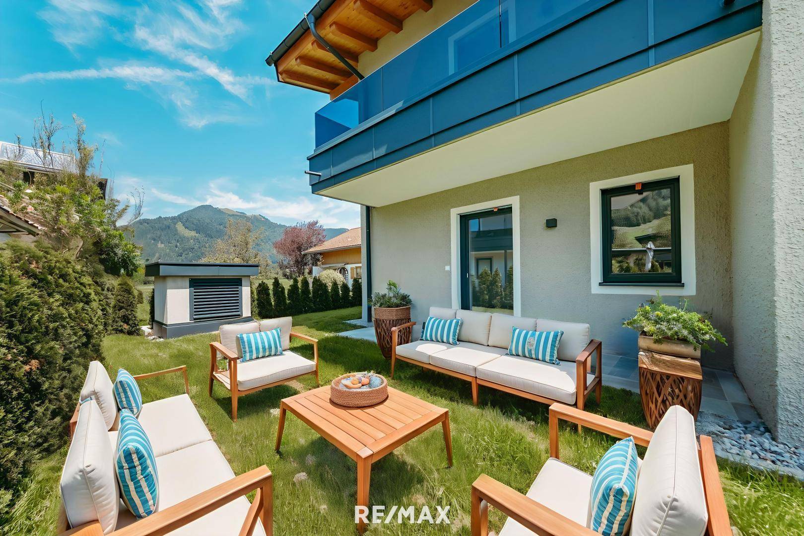 Gemütlicher Sitzbereich im Garten mit modernen Holzmöbeln und Bergblick.