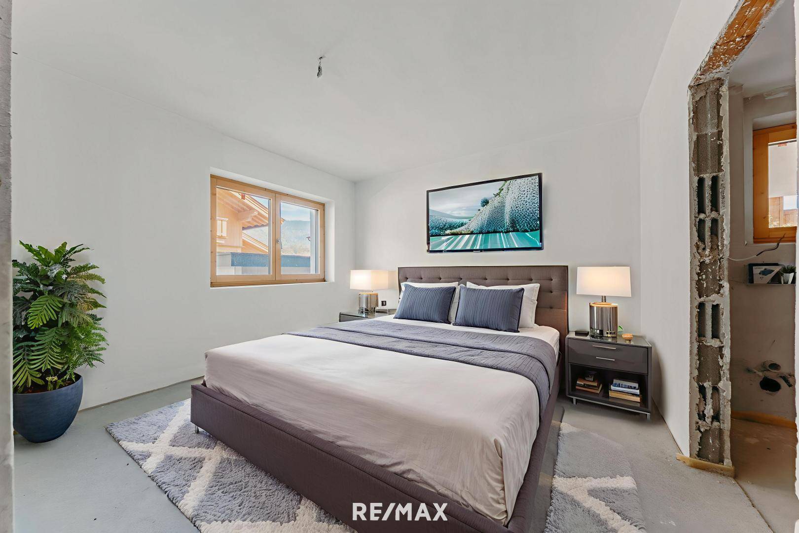 Helles Schlafzimmer mit großem Bett, moderner Einrichtung und Blick auf die umliegende Natur.