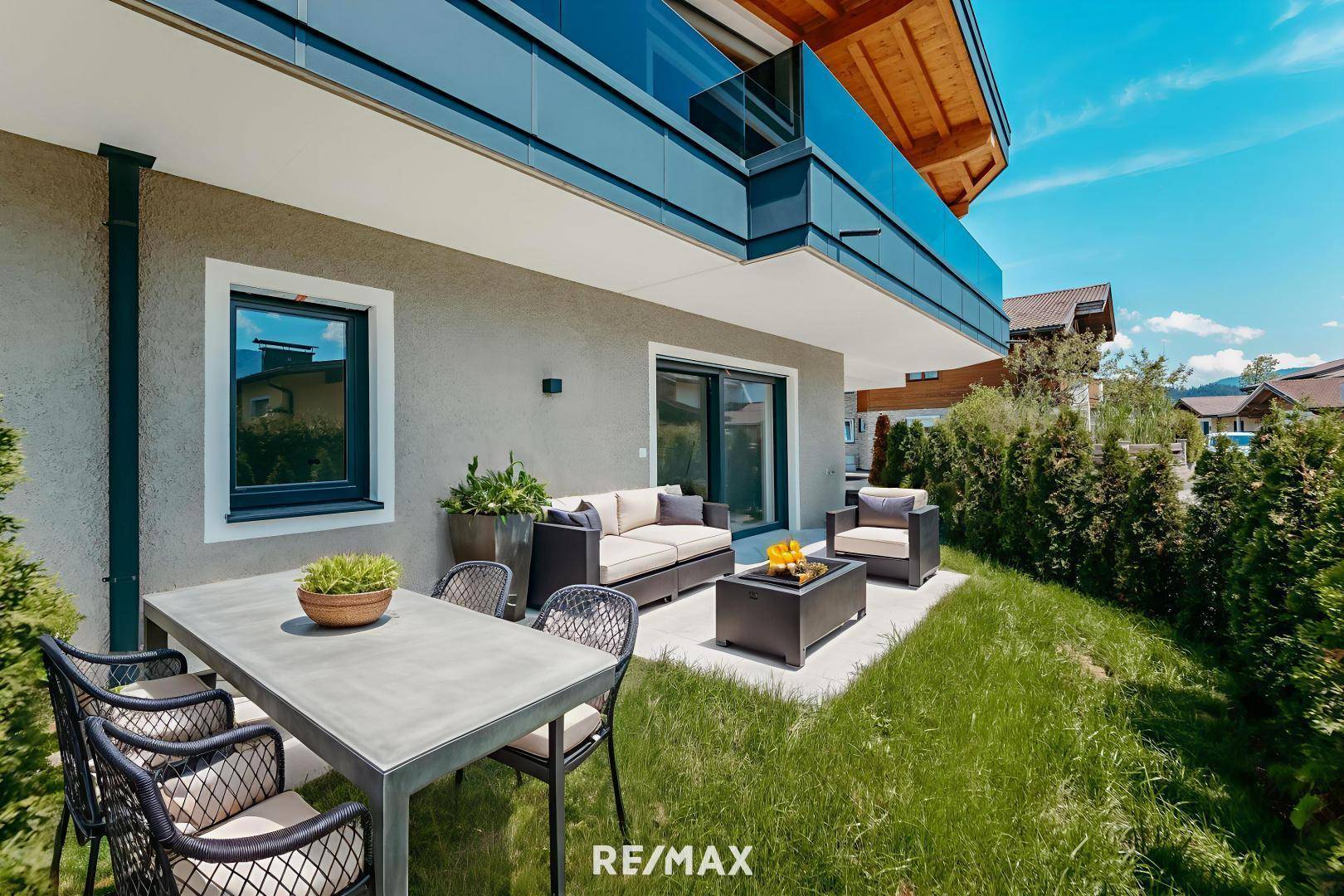 Möblierte Terrasse mit Essbereich und Lounge-Möbeln, umgeben von einem gepflegten Garten.