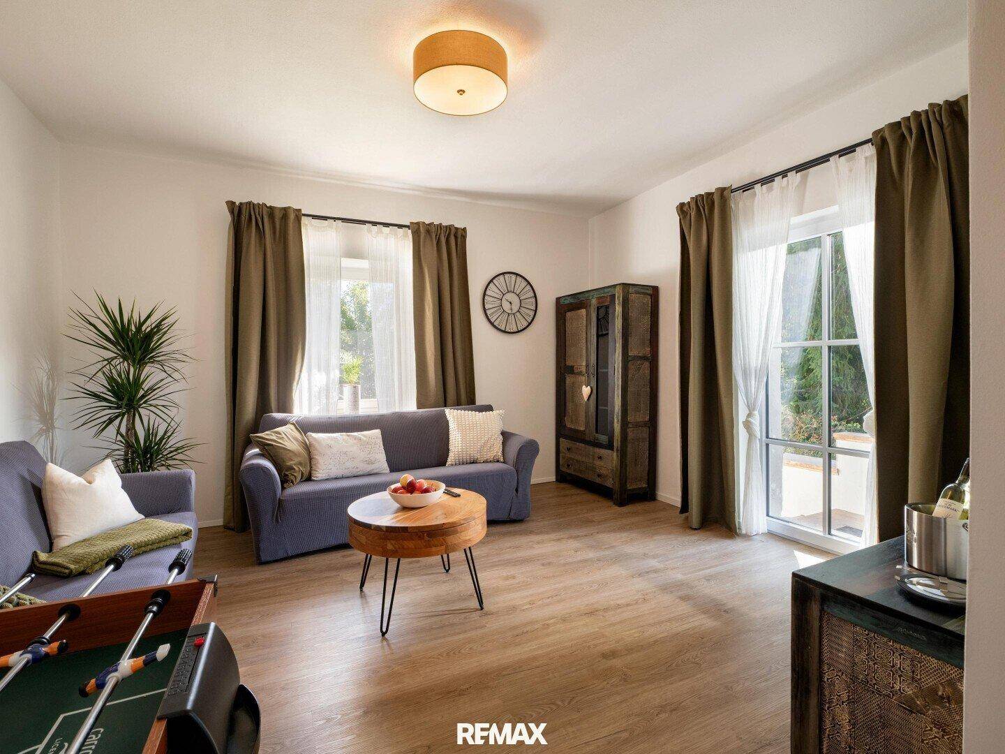 Gemütliches Wohnzimmer mit Sofa, Couchtisch und einem Tischfußballtisch, hell und einladend.