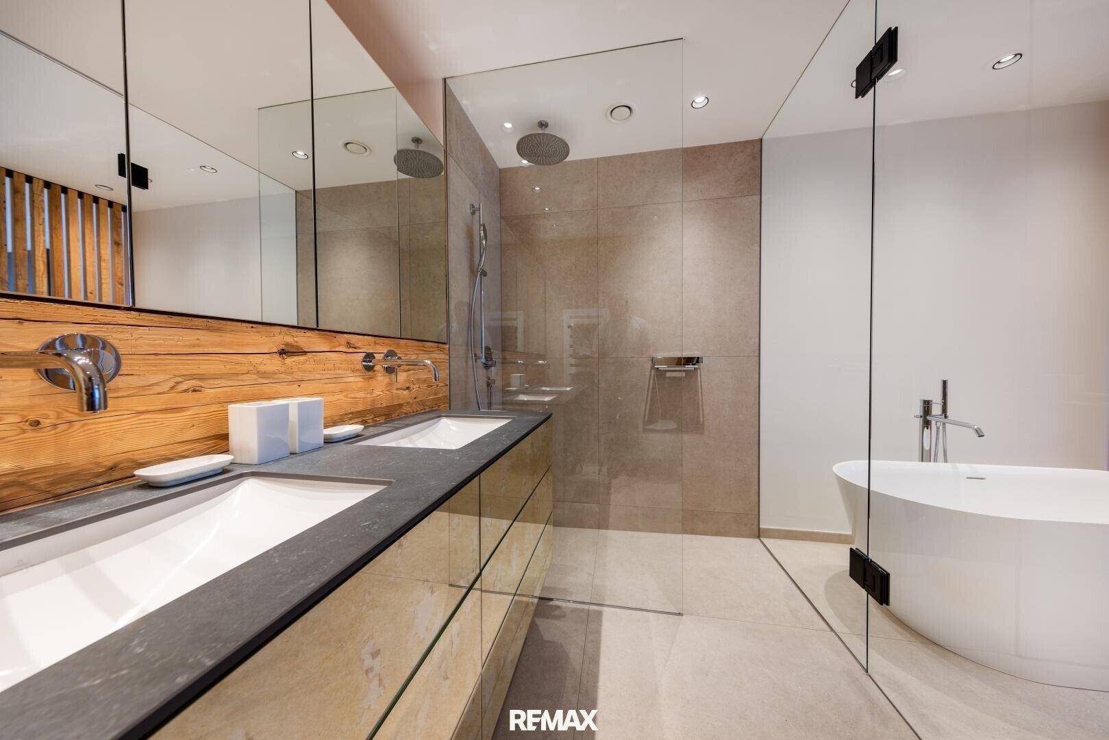 Luxuriöses Badezimmer mit Doppelwaschbecken, freistehender Badewanne und großer begehbarer Dusche.