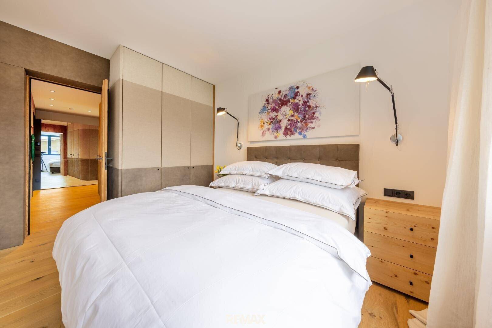 Gemütliches Schlafzimmer mit Holzboden, Einbauschränken und moderner Kunst an der Wand.