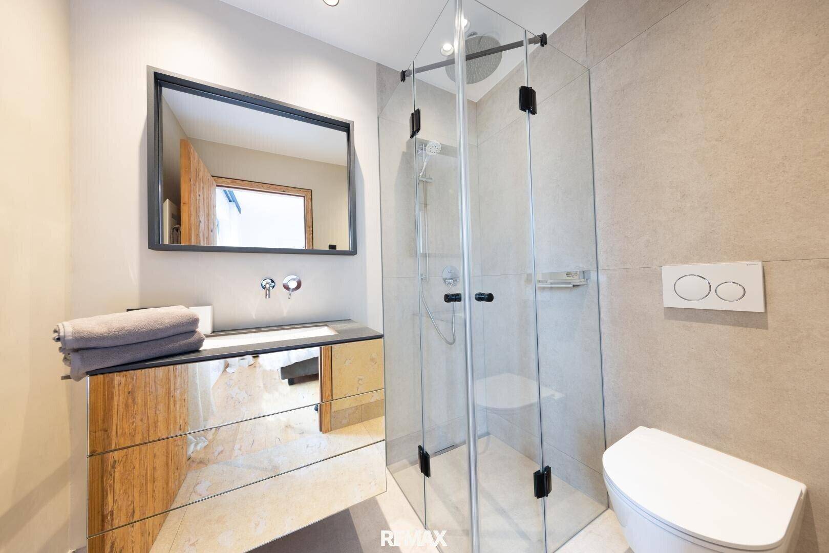 Modernes Badezimmer mit begehbarer Dusche, Wand-WC und stilvollem Waschbeckenunterschrank.