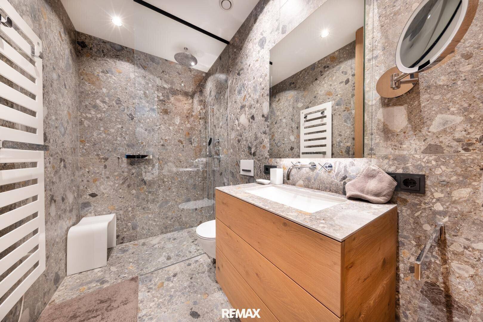 Elegantes Badezimmer mit großformatigen Fliesen, schwebendem Waschtisch und begehbarer Dusche.