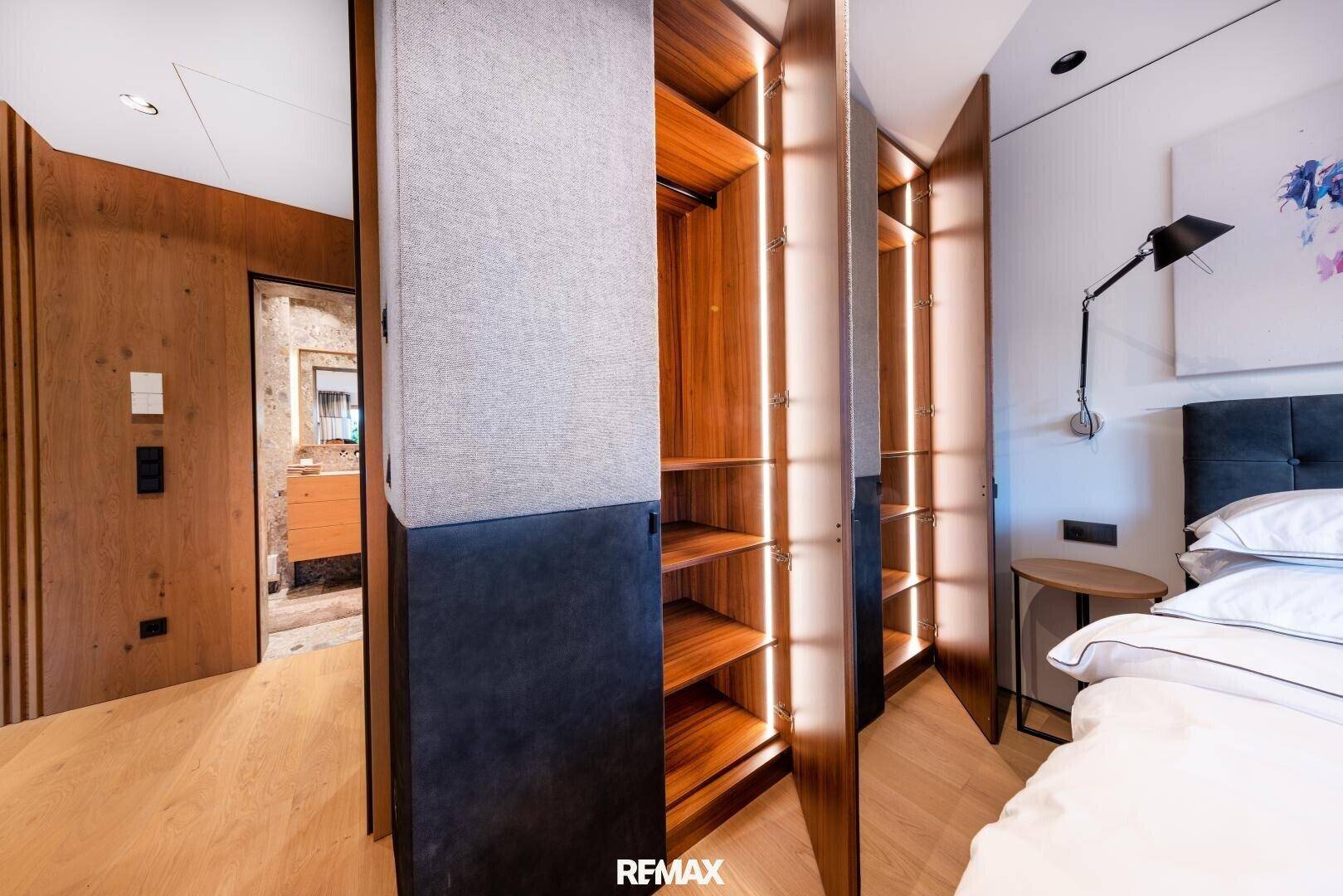 Schlafzimmer mit integriertem Kleiderschrank, Holzboden und moderner Wandleuchte.