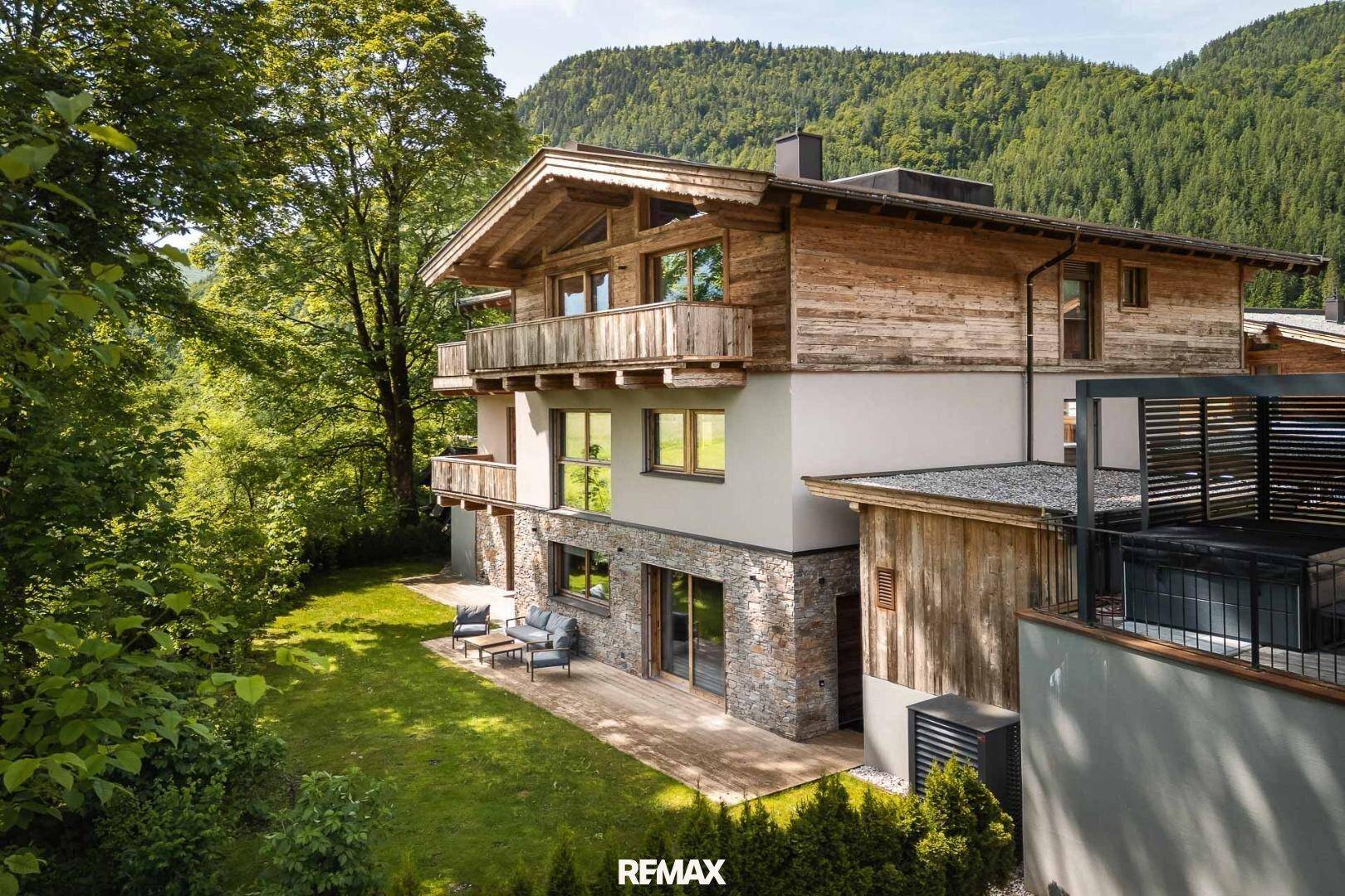Chalet-Stil Haus mit Holzfassade, Steinelementen und gepflegtem Gartenbereich.
