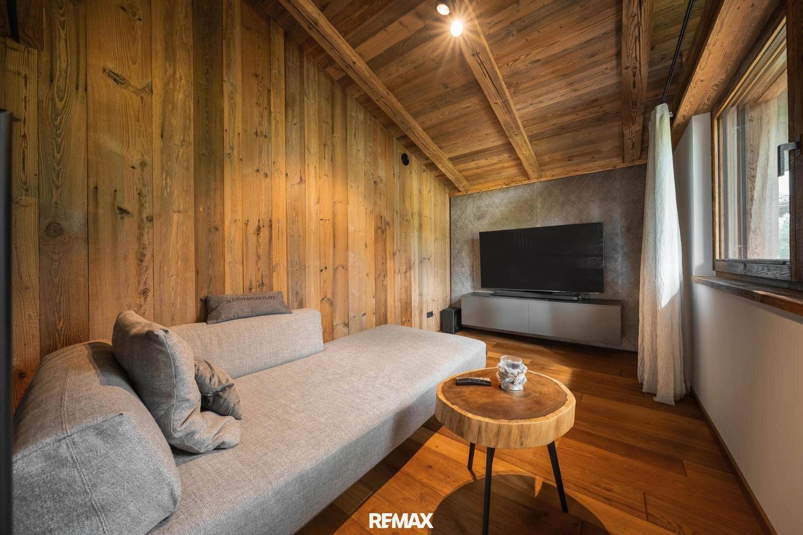 Gemütlicher Wohnbereich mit Holzvertäfelung, bequemer Couch und Fernseher an der Wand.