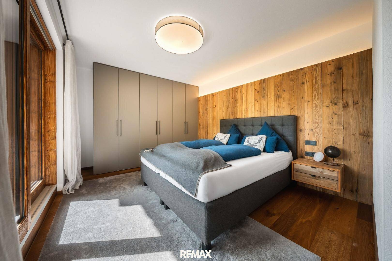 Schlafzimmer mit Holzboden, Einbauschränken und großem Fenster.