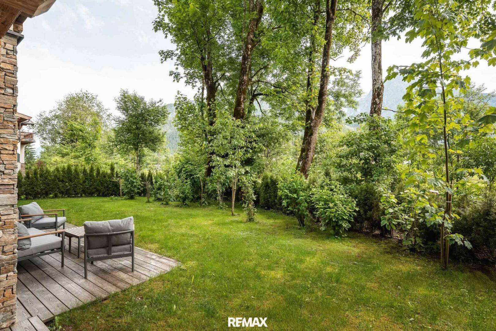 Großer, grüner Garten mit altem Baumbestand und gemütlicher Sitzgelegenheit.