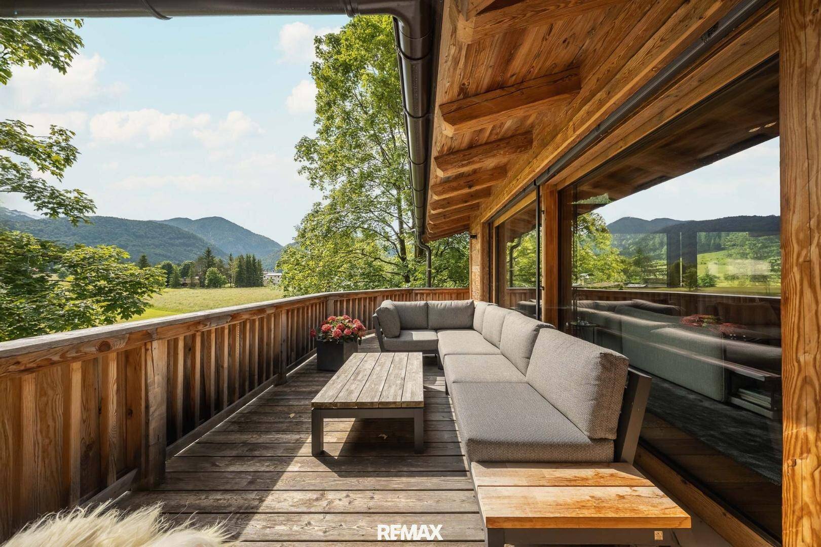 Großer Holzbalkon mit bequemen Lounge-Möbeln und weitem Blick auf die Berge.
