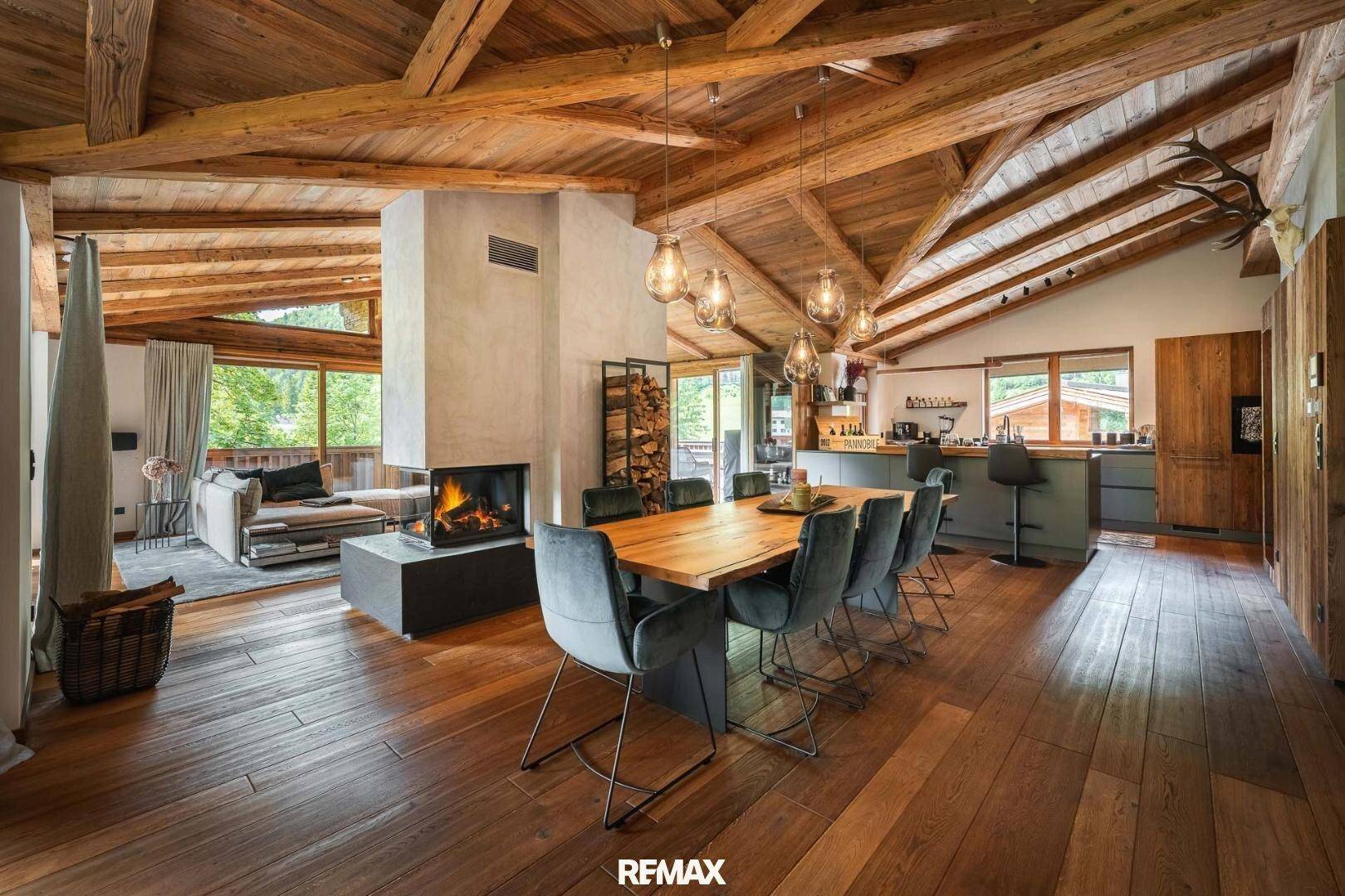 Geräumiger Wohn-Essbereich mit Holzbalkendecke, Kamin und offener Küche.