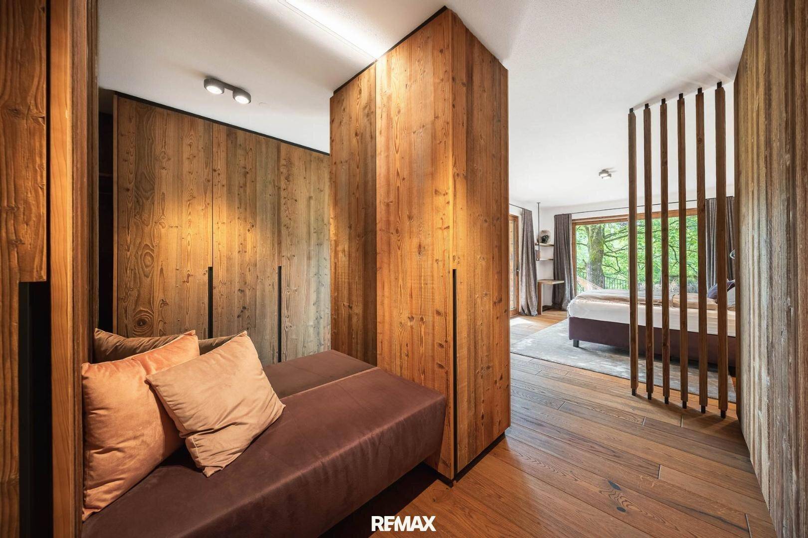 Schlafzimmer mit Holzwänden, Einbauschränken und gemütlicher Sitzecke.
