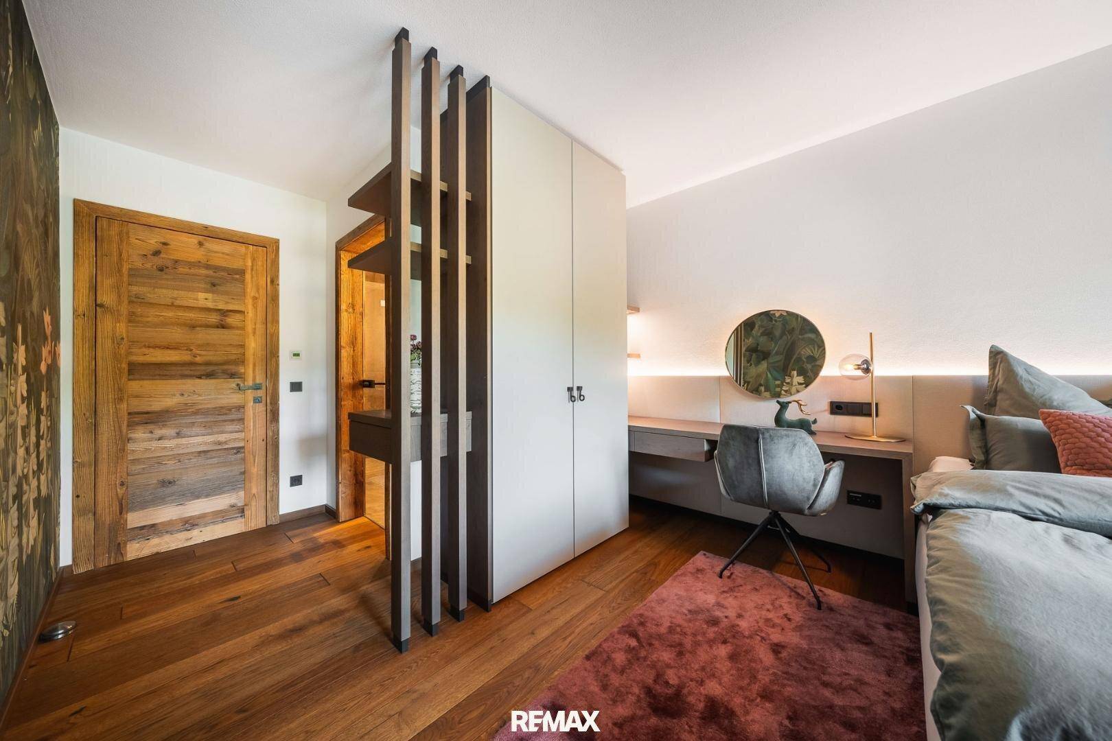 Schlafzimmer mit Holzboden, integriertem Schrank und dekorativem Raumteiler.