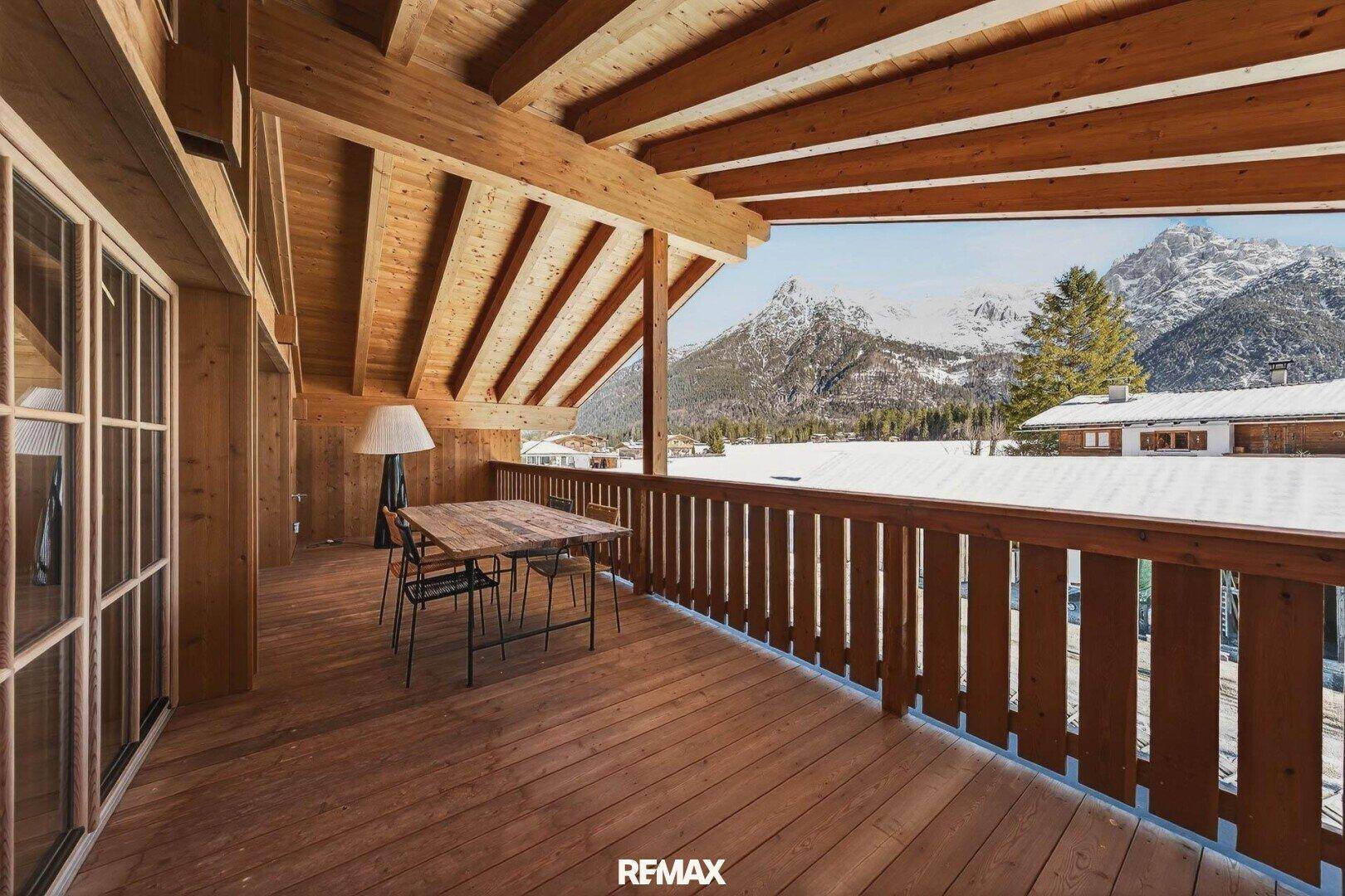 Geräumiger Holzbalkon mit Sitzgelegenheiten und atemberaubendem Panoramablick auf die verschneiten Berge.