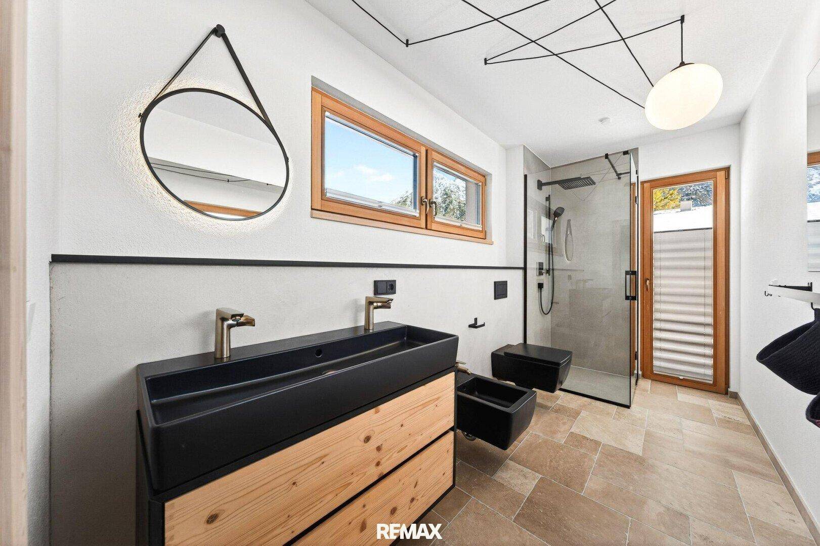 Stilvolles Badezimmer mit Doppelwaschbecken, moderner Dusche und Fenster für Tageslicht.
