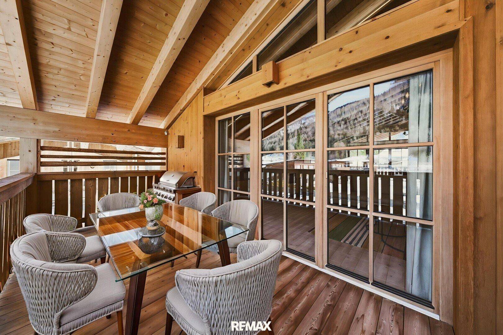 Überdachter Balkon mit Esstisch, Grillbereich und Holzboden, ideal für Mahlzeiten im Freien.