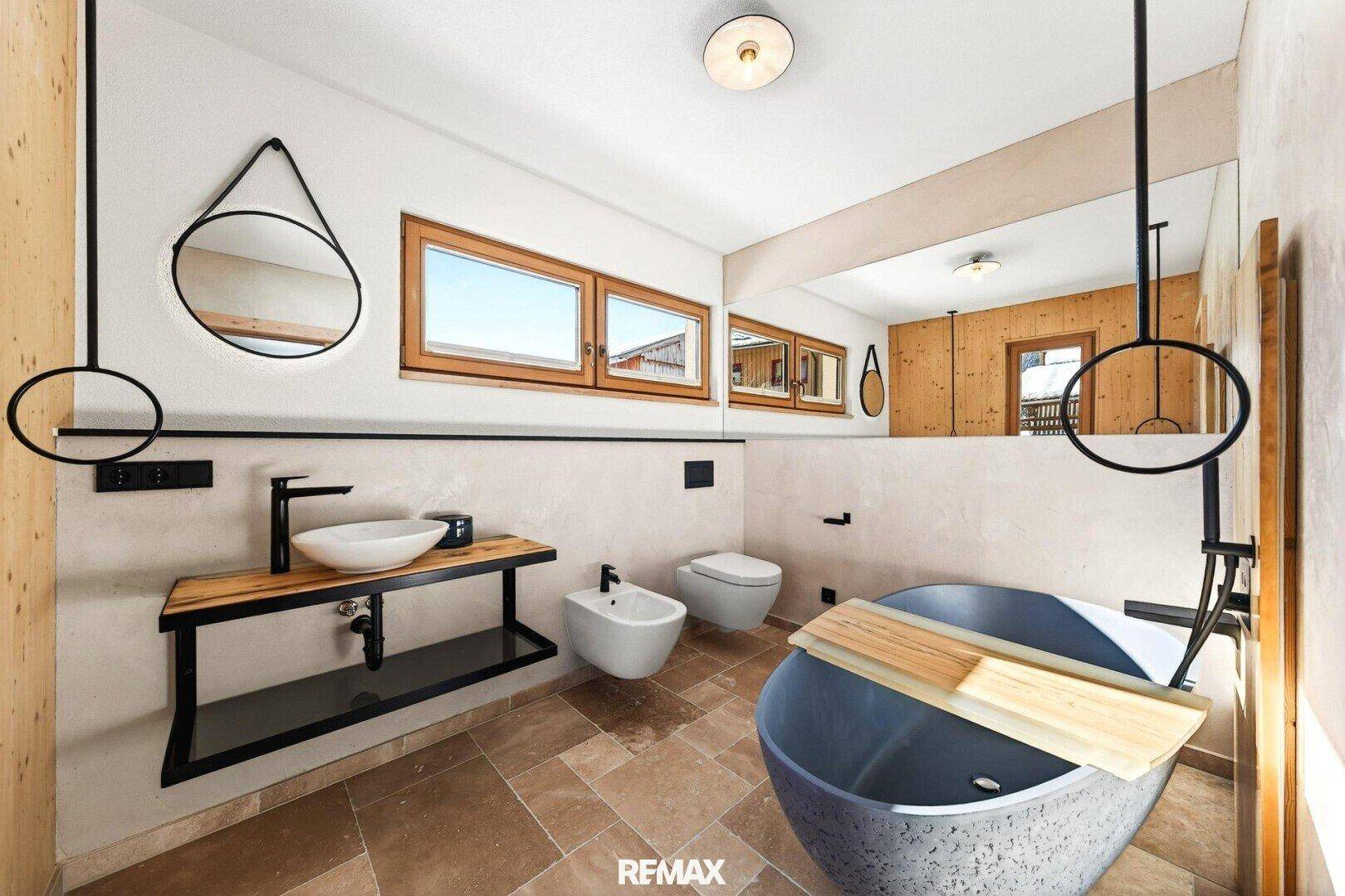 Modernes Badezimmer mit freistehender Badewanne, Doppelwaschbecken und Fenster.
