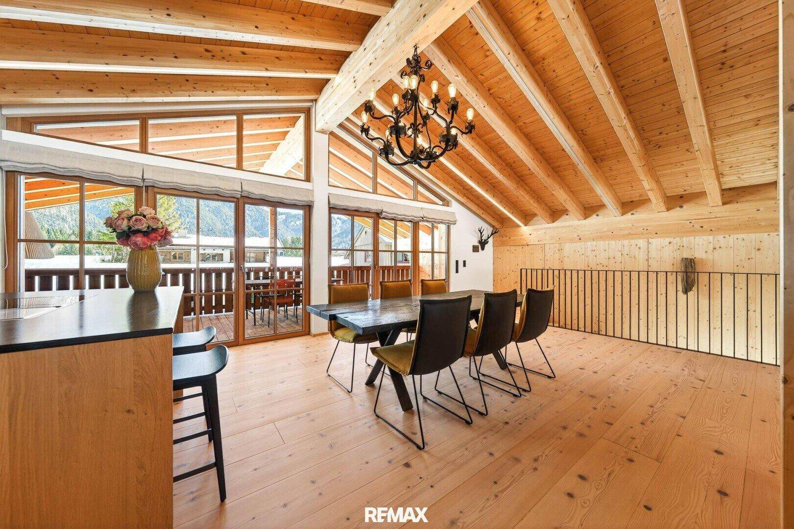 Heller Essbereich mit großem Holztisch, modernen Stühlen und Zugang zum Balkon.