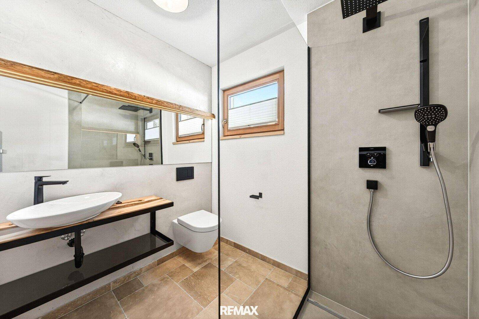 Modernes Badezimmer mit begehbarer Dusche, Wand-WC, Einzelwaschbecken und Fenster für Tageslicht.