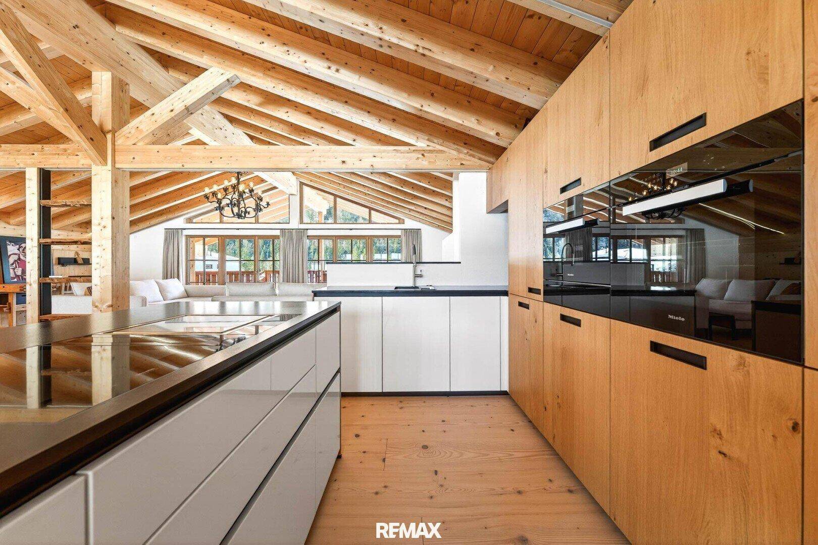 Moderne Küche mit Holzelementen, weißen Fronten und hochwertigen Einbaugeräten.