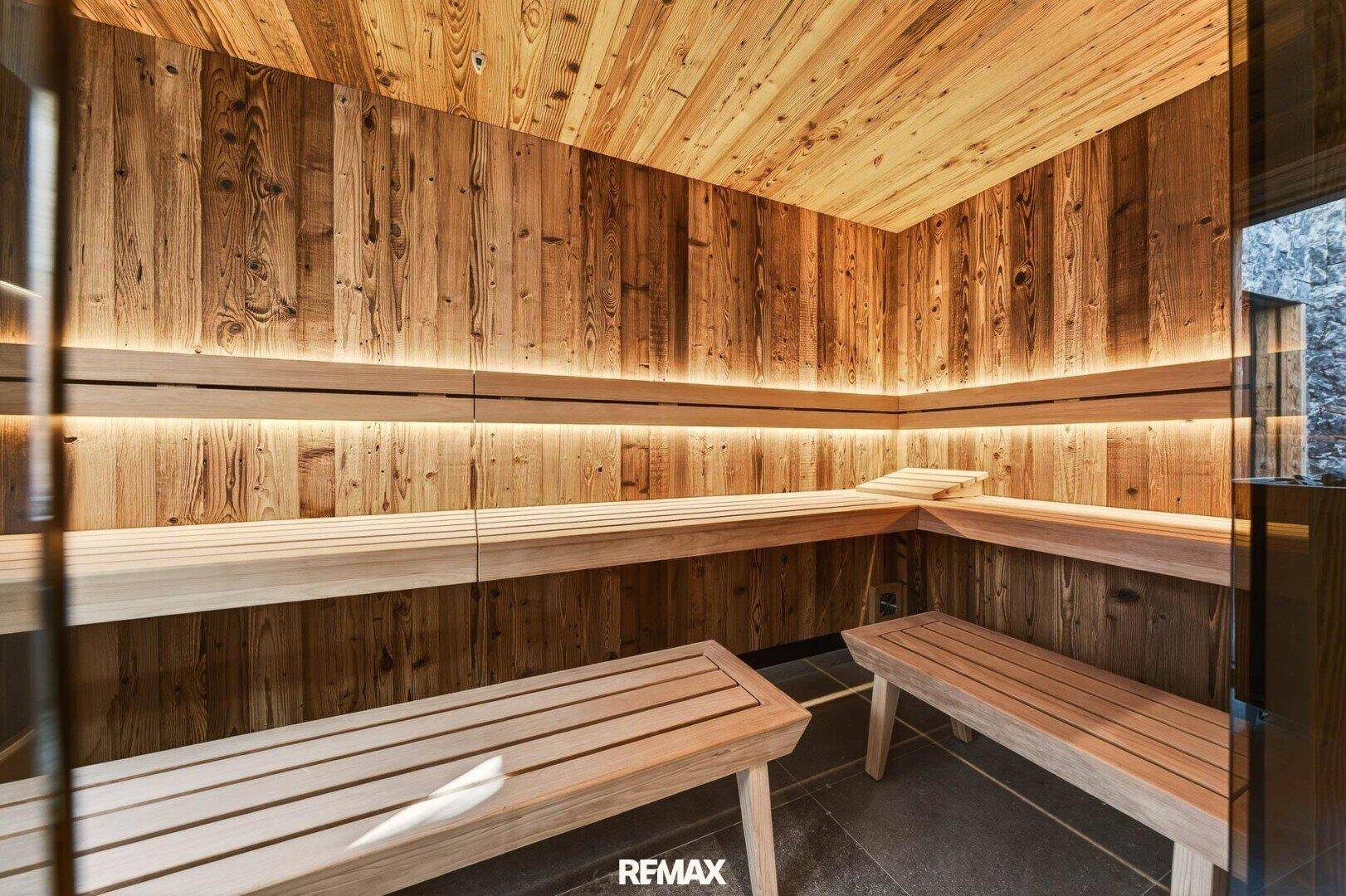Moderne Holzsauna mit indirekter Beleuchtung und bequemen Bänken für Entspannung.