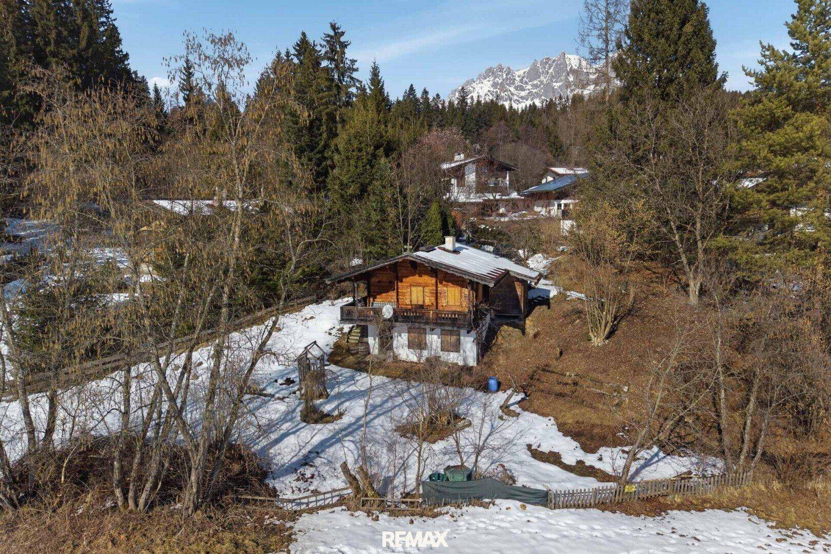 Charmantes Holzhaus mit Balkon und schneebedecktem Dach, eingebettet in eine winterliche Landschaft.