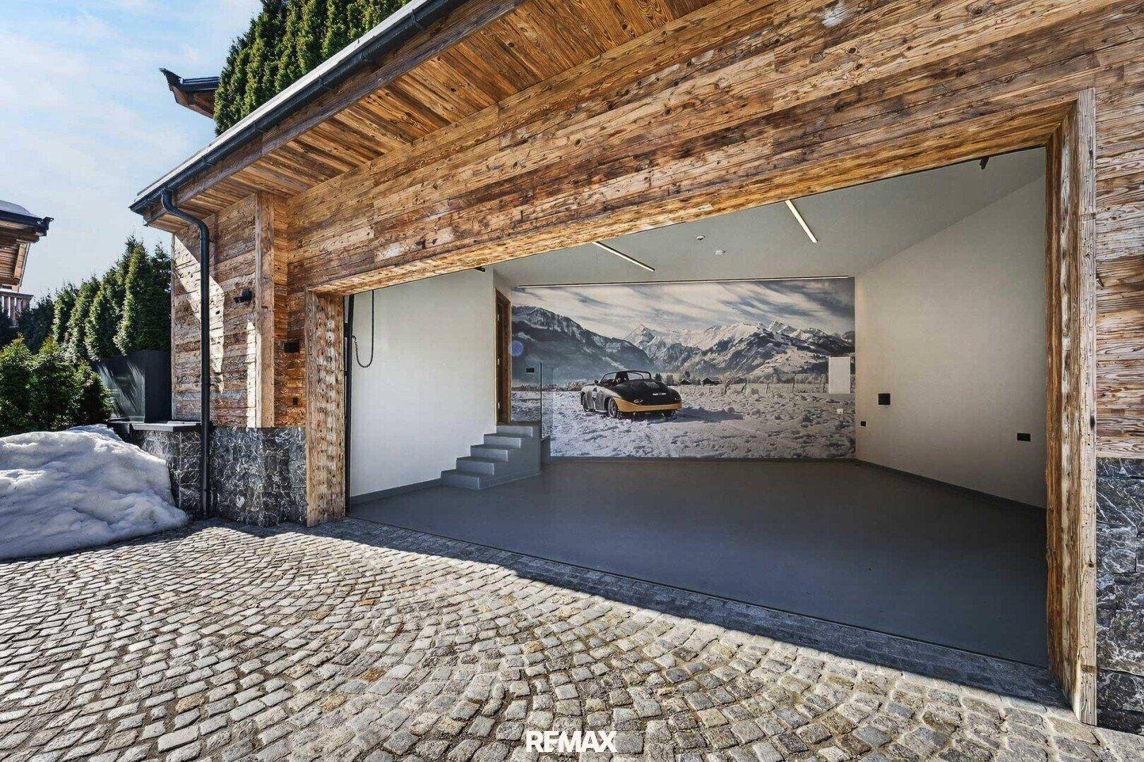 Offene Garage mit Holzelementen und einem Wandbild, das eine Berglandschaft zeigt.