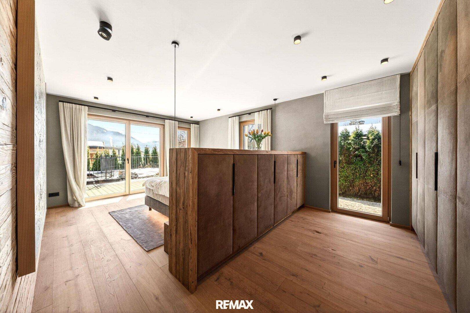 Helles Schlafzimmer mit Holzboden, Einbauschränken und direktem Zugang zur Terrasse.