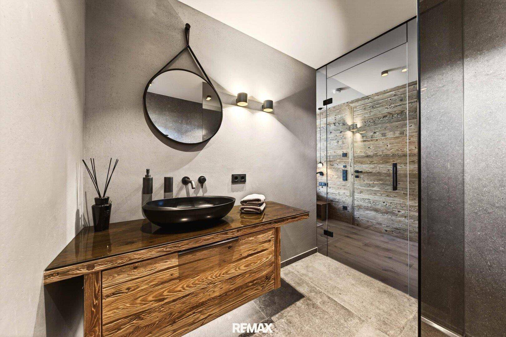 Modernes Badezimmer mit Holzwaschtisch, schwarzem Waschbecken und begehbarer Dusche.