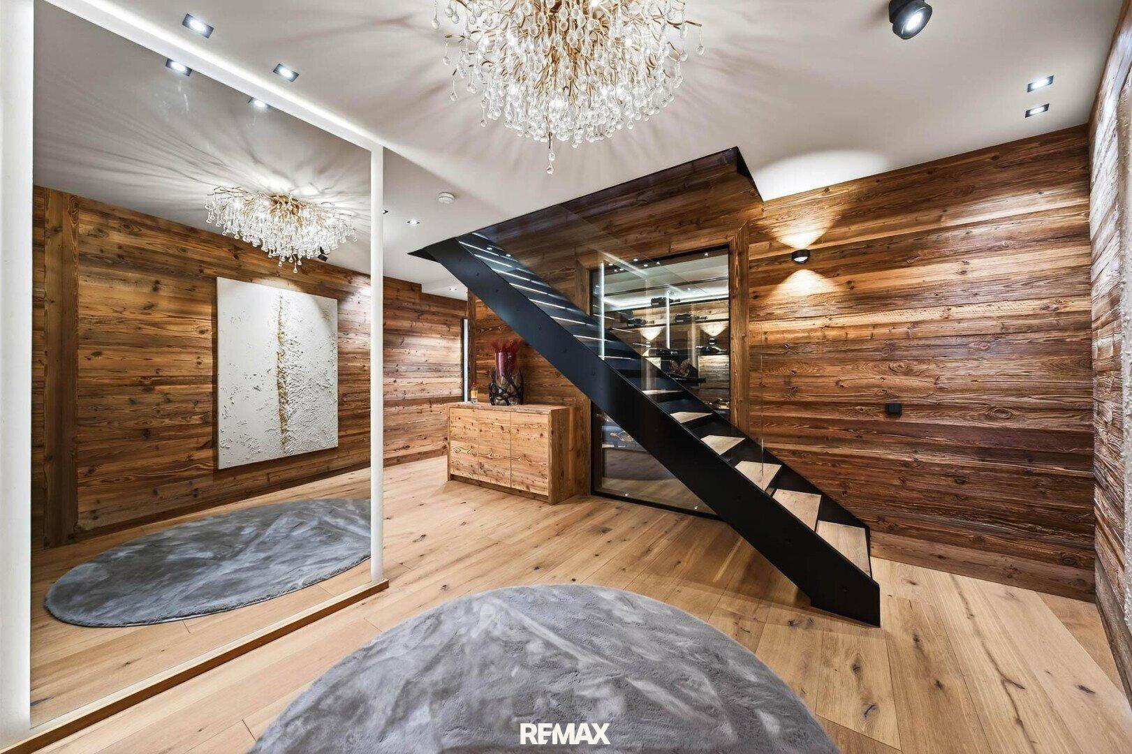 Eleganter Flurbereich mit moderner Treppe, Holzwänden und einem großen Spiegel.