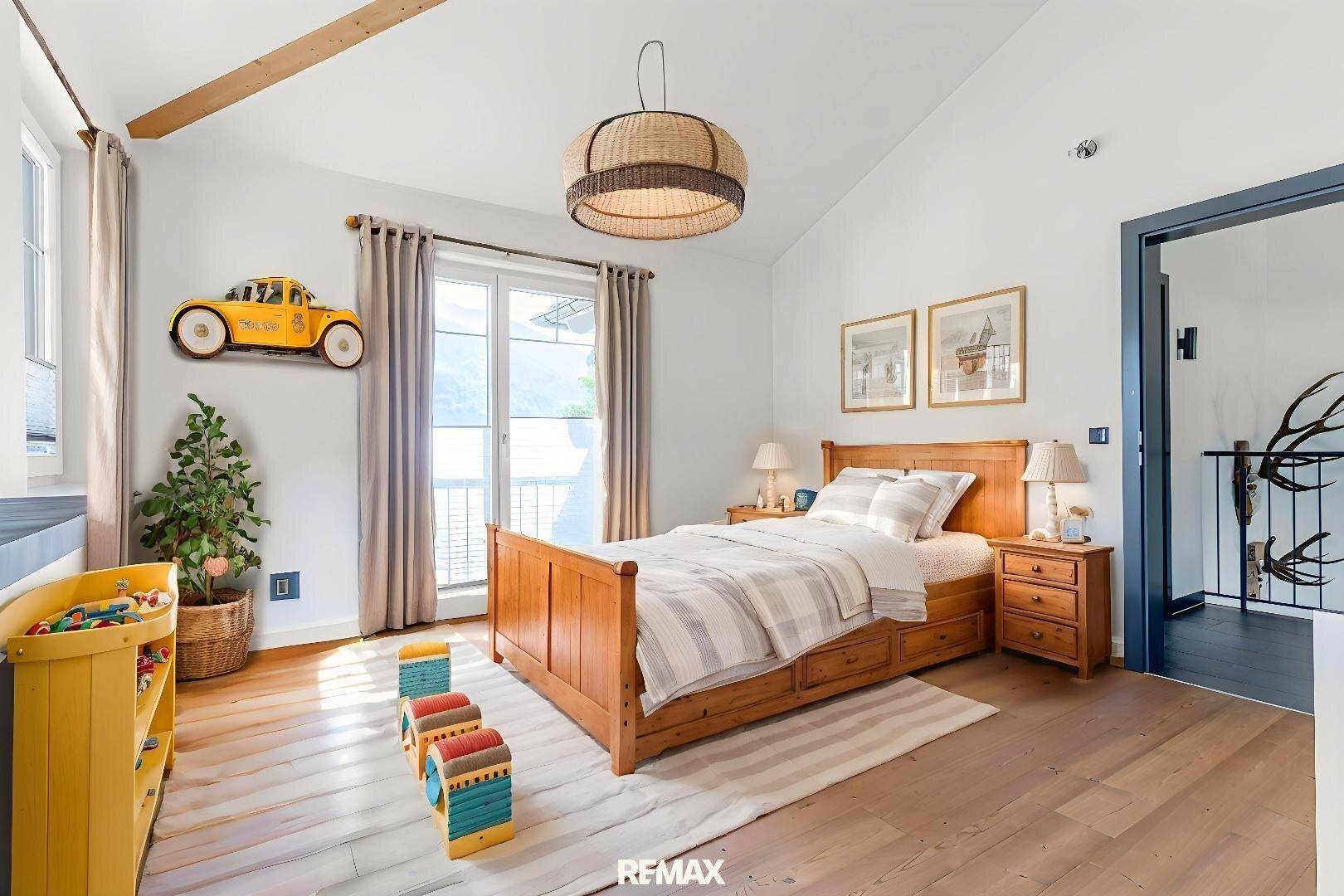 Helles Schlafzimmer mit Holzbett, Dachschräge und Zugang zu einem französischen Balkon.