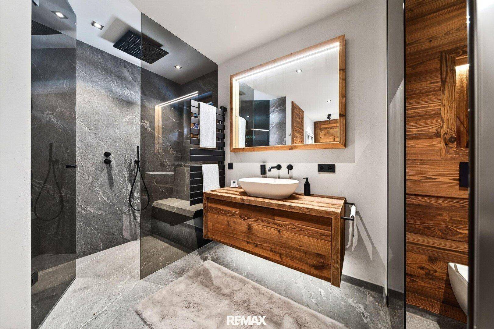 Modernes Badezimmer mit begehbarer Dusche, Holzwaschtisch und eleganten Steinfliesen.