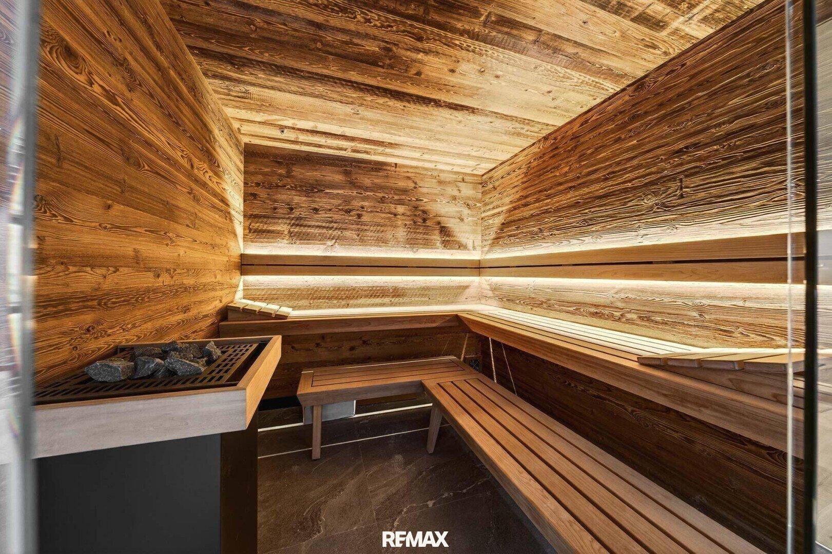 Moderne Holzsauna mit integrierter Beleuchtung und traditionellem Saunaofen für Entspannung.