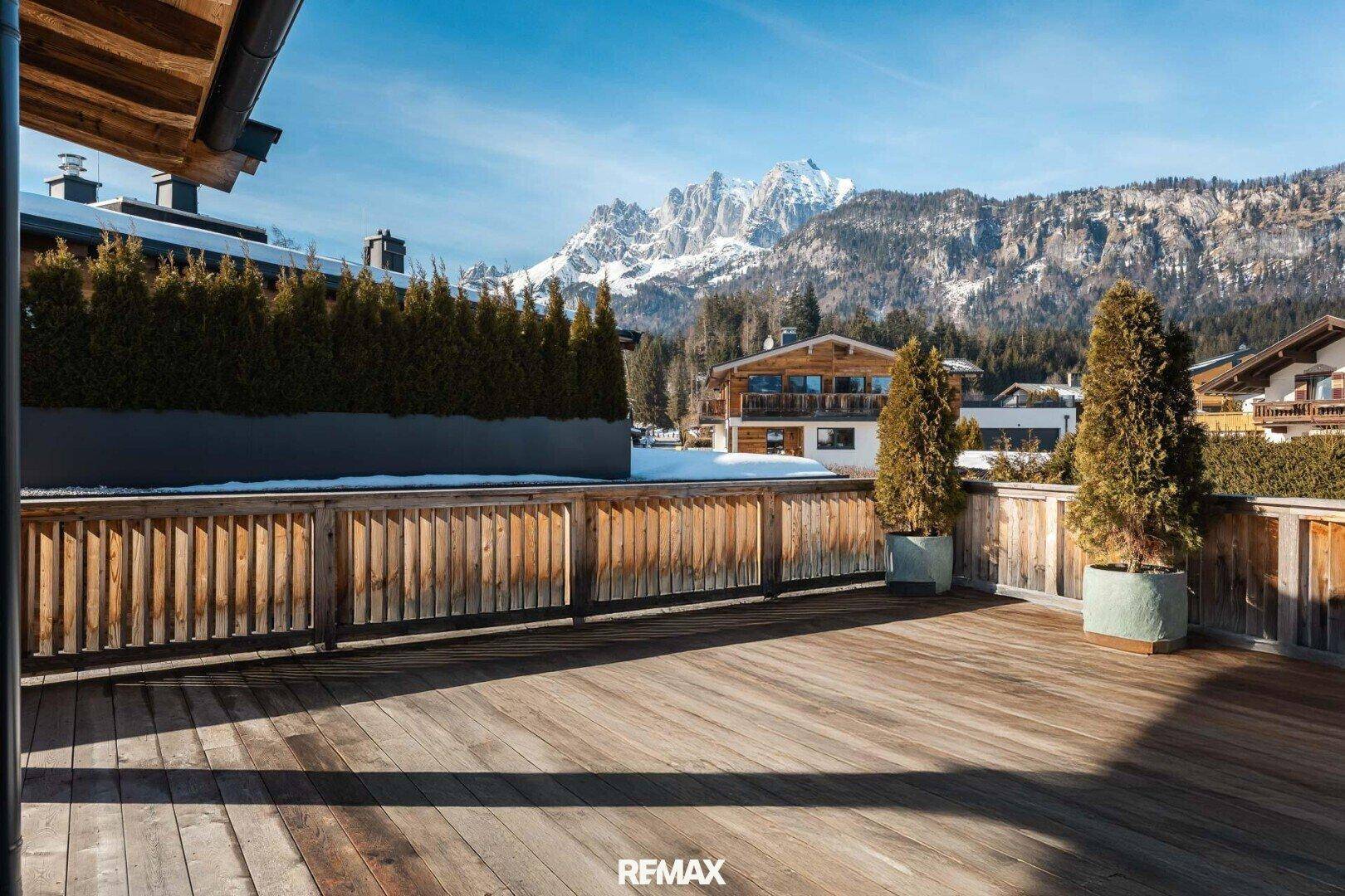 Große Holzterrasse mit Bergblick und Pflanzenkübeln, ideal für sonnige Tage.