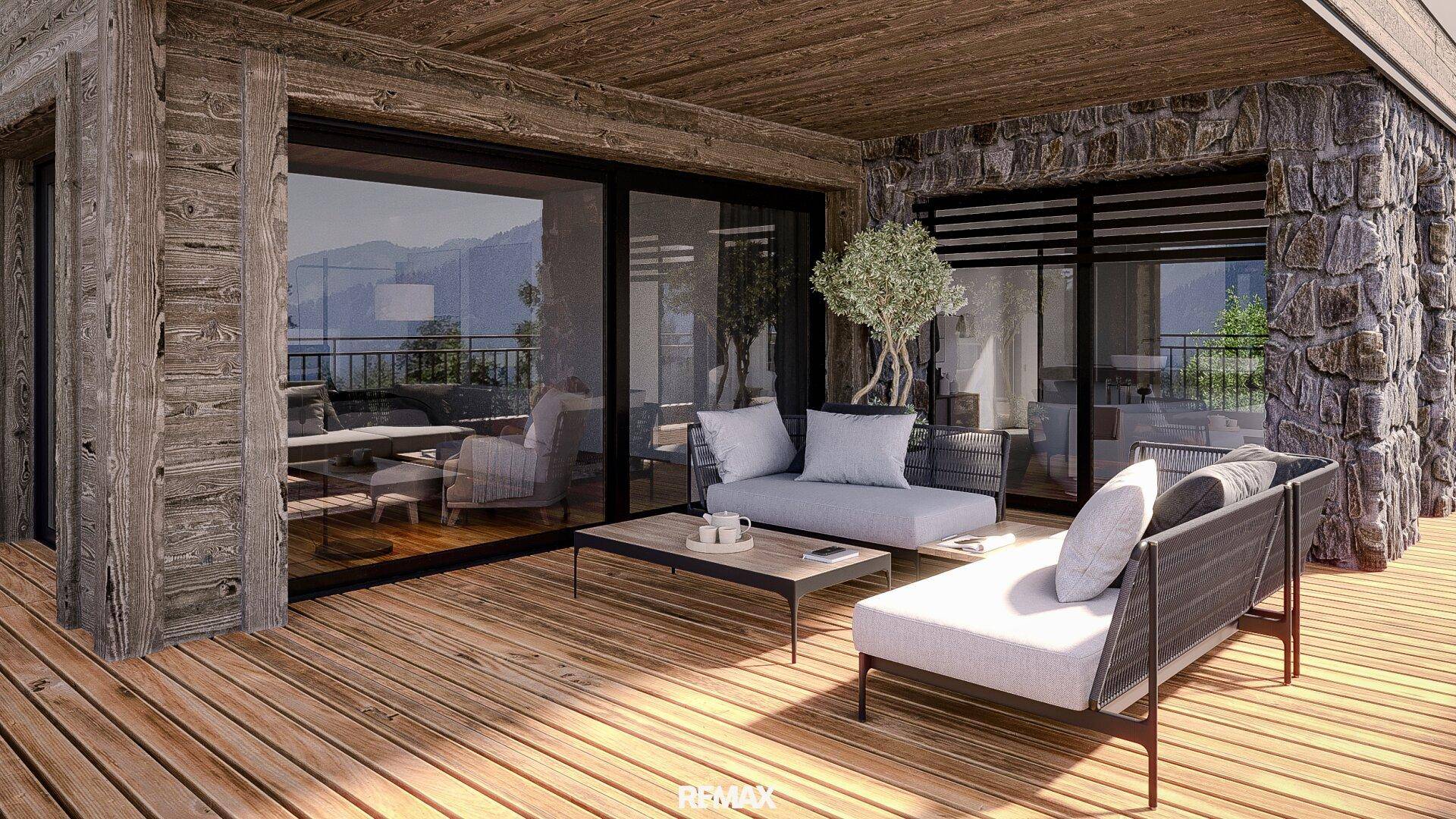 Geräumiger Balkon mit Holzboden, bequemen Lounge-Möbeln und weitem Blick auf die Berge.