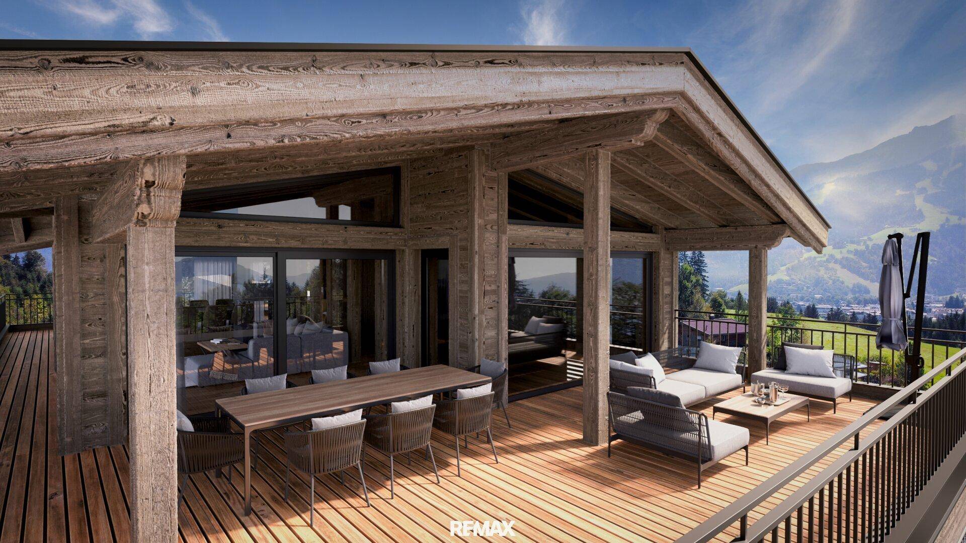 Großer Balkon mit Essbereich und Lounge-Möbeln, umgeben von der Holzarchitektur des Chalets.