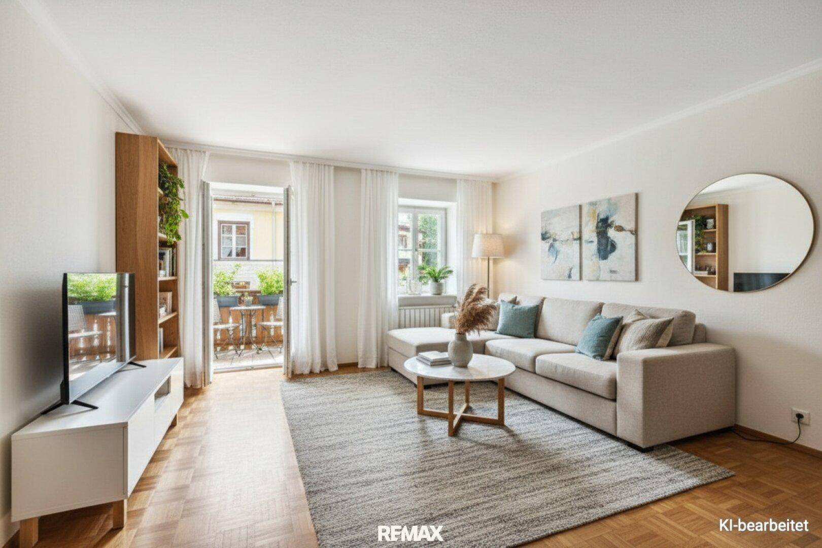 Helles Wohnzimmer mit bequemem Sofa, Couchtisch und Zugang zu einem kleinen Balkon.