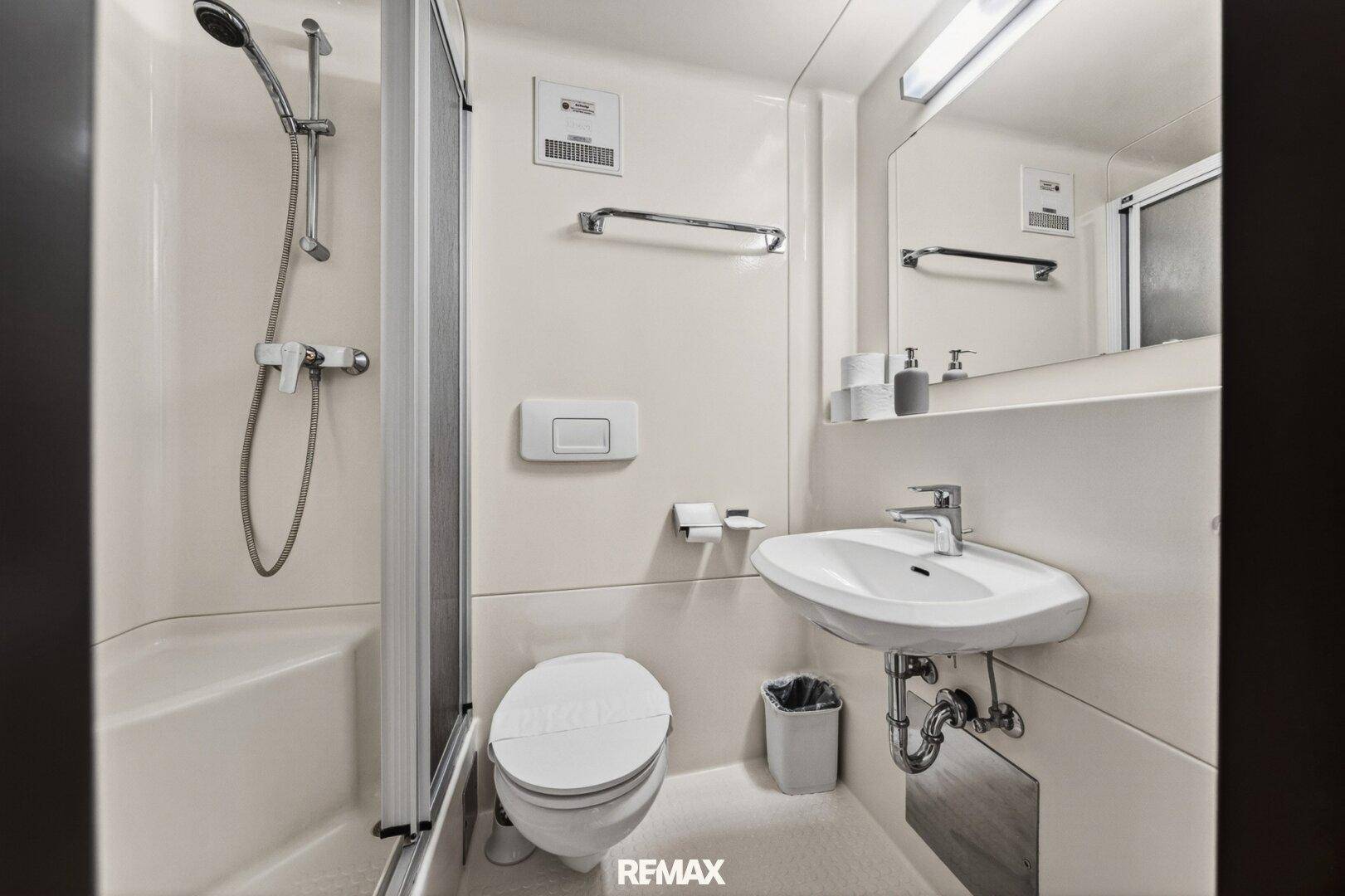 Kompaktes Badezimmer mit Dusche, WC und Waschbecken in heller, funktionaler Ausstattung.