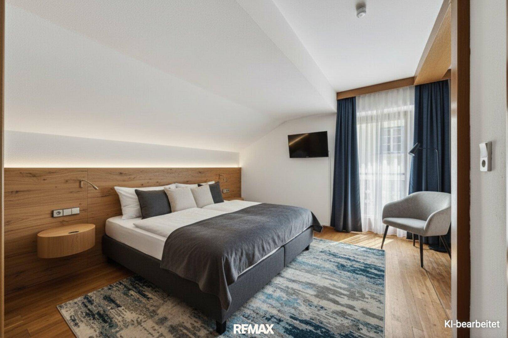 Elegantes Schlafzimmer mit großem Bett, Holzboden und indirekter Beleuchtung an der Holzwand.