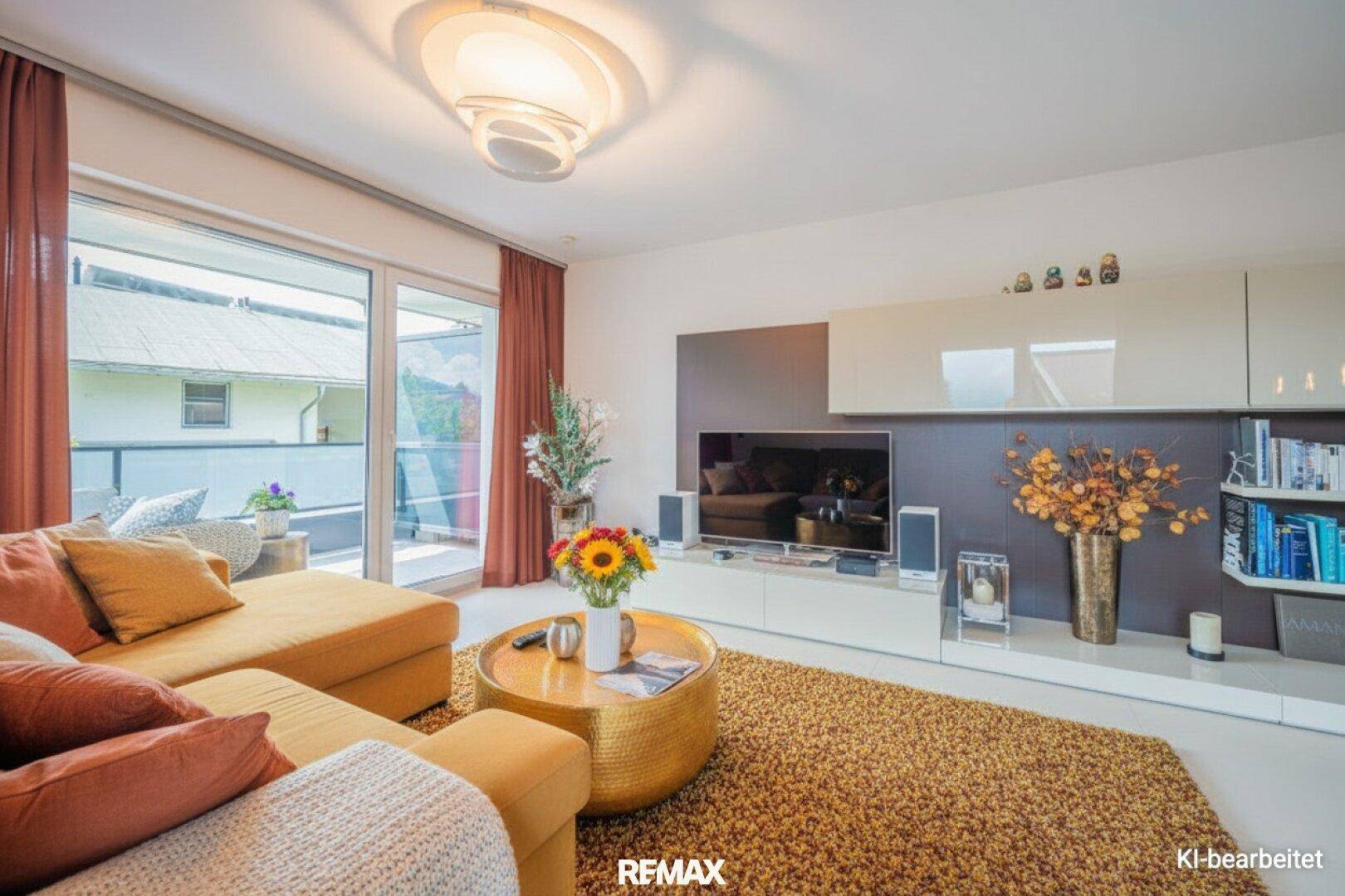 Gemütliches Wohnzimmer mit großem Sofa, Teppich und Zugang zu einem Balkon, hell und modern eingerichtet.