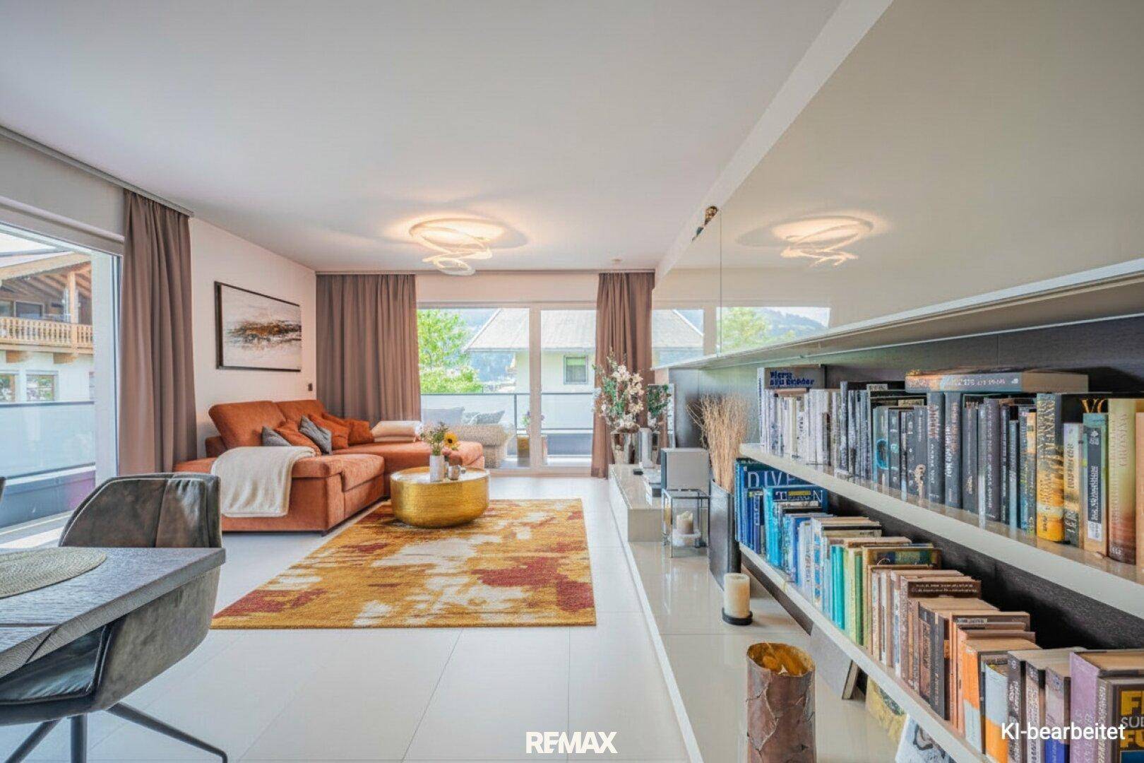 Offener Wohnbereich mit Sofa, Bücherregal und Zugang zum Balkon, hell und modern gestaltet.