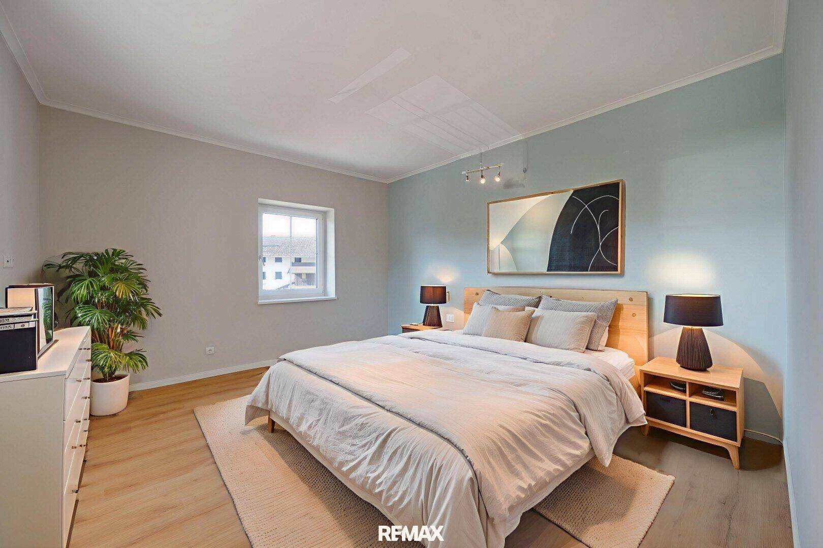 Gemütliches Schlafzimmer mit hellem Holzbett, moderner Kunst und einem Fenster mit Blick ins Grüne.