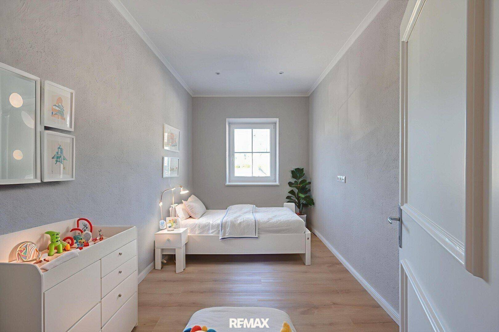 Helles Schlafzimmer mit Holzboden, einem Fenster und einem Wickeltisch für Kinder.