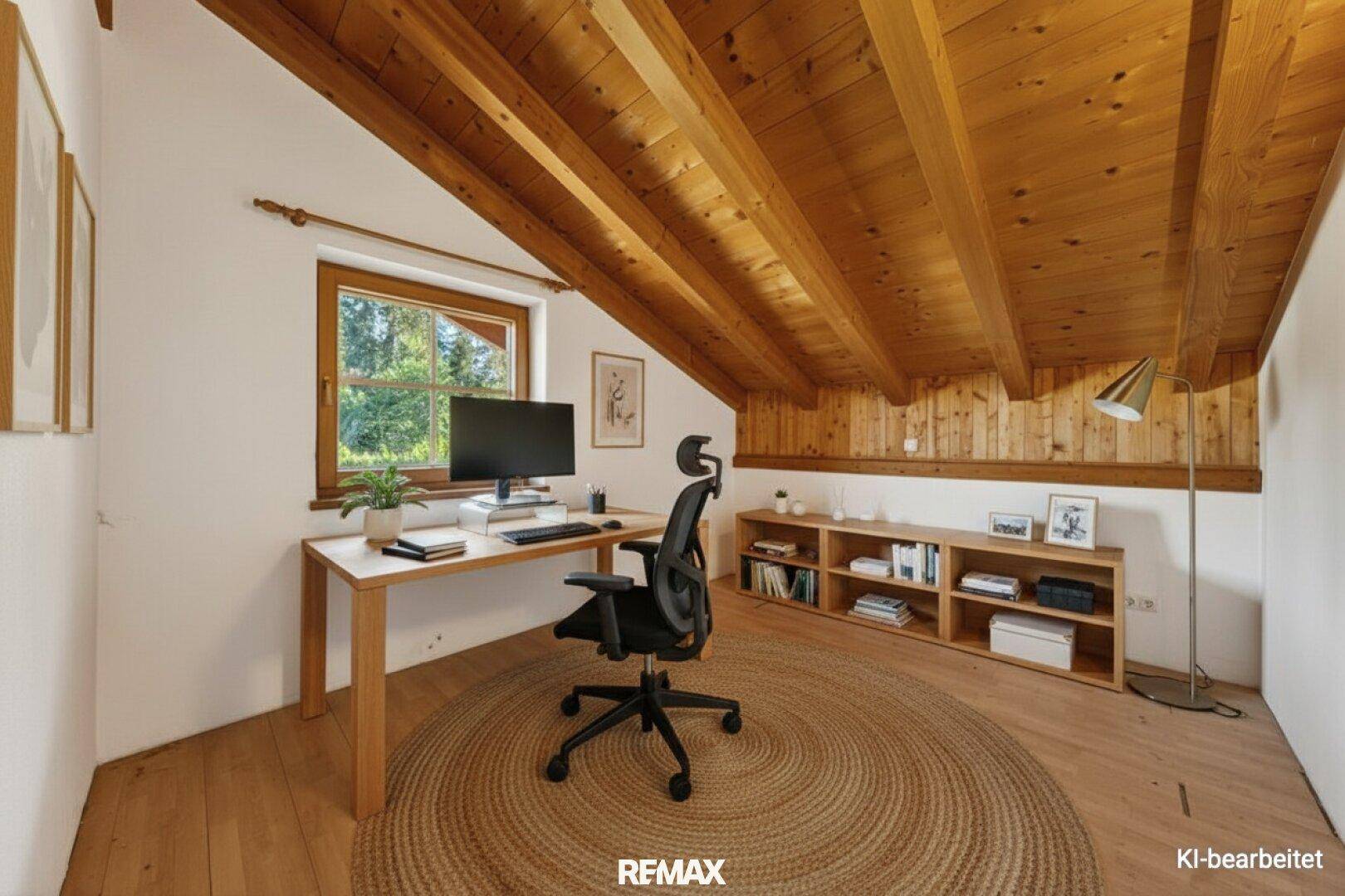 Helles Arbeitszimmer mit Holzbalkendecke, Dachschräge und Blick ins Grüne.