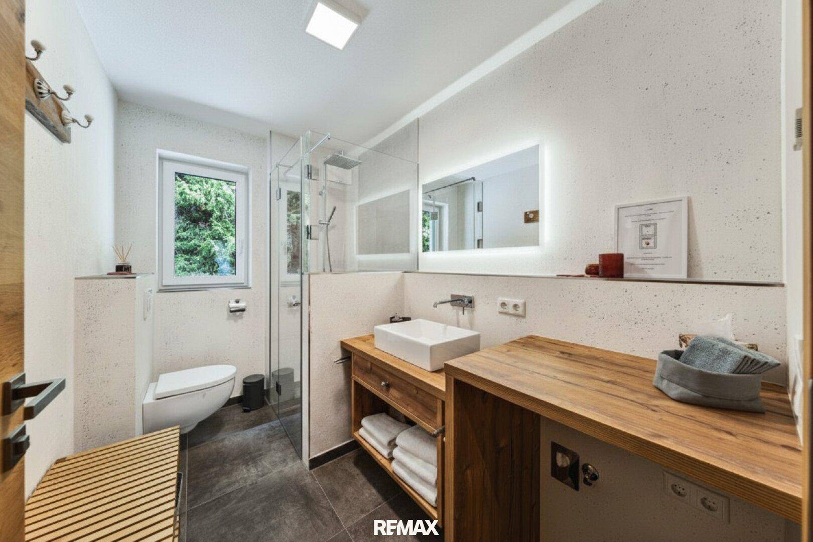 Modernes Badezimmer mit begehbarer Dusche, Holzwaschtisch und Fenster für Tageslicht.