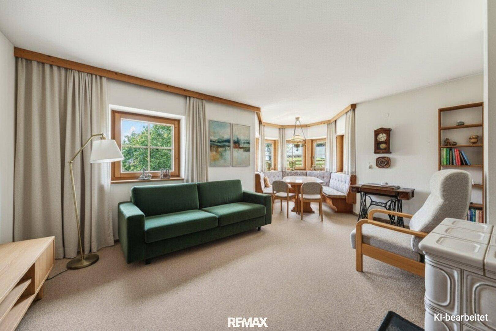 Gemütlicher Wohn-Essbereich mit grünem Sofa, Eckbank und traditionellem Kachelofen.