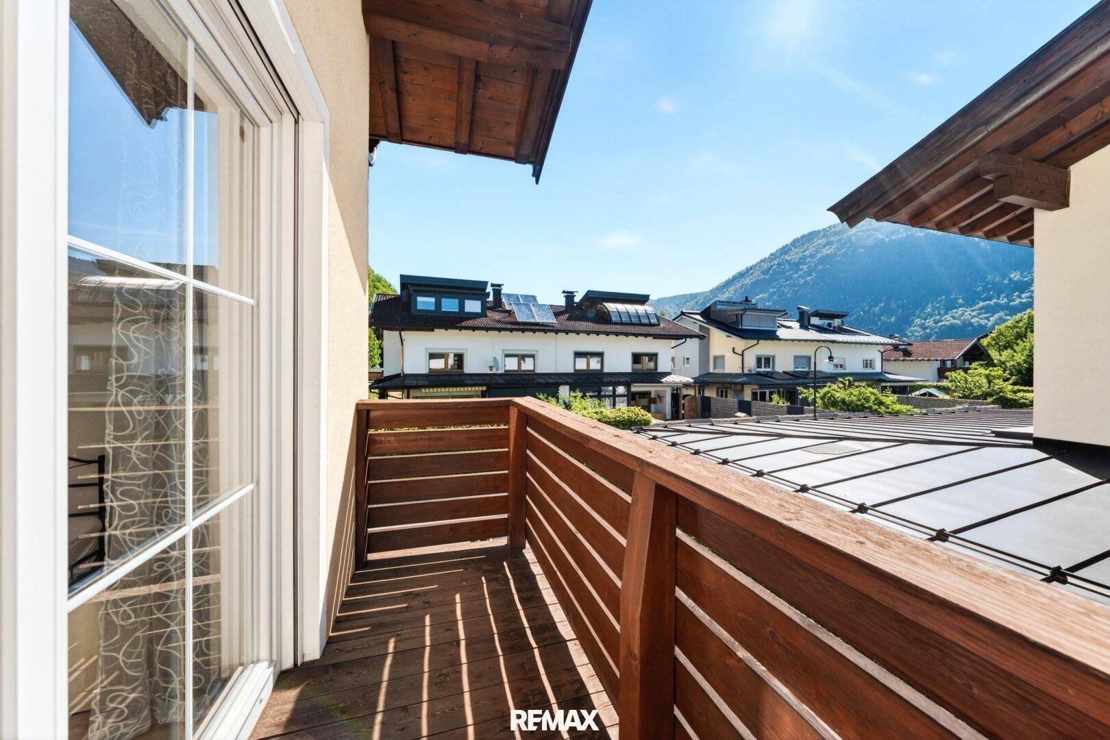 Kleiner Holzbalkon mit Bergblick und Sonnenschein.